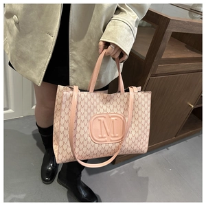 Detail of light pink tote bag featuring all-over M letter print and circular logo
