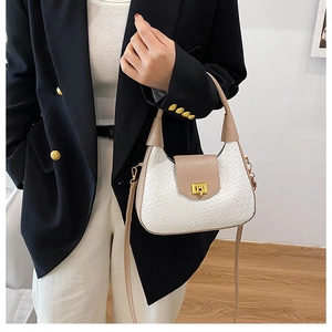 Close-up of white crocodile texture bag with khaki leather trim and gold twist lock