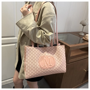 Detail of pink tote bag with M-pattern monogram and embossed logo shown on model