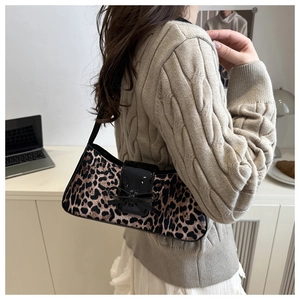 Sac baguette léopard avec nœud noir porté à l'épaule dans un décor intérieur cosy