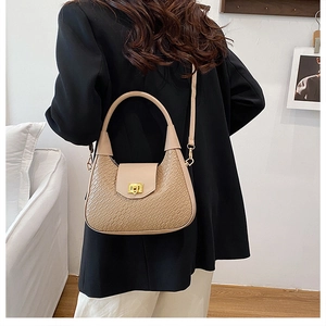 Detail of the woven texture and golden rectangular twist lock on this beige crescent bag