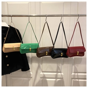 Detail view of five colors of glossy patent leather armpit bags with gold metal locks