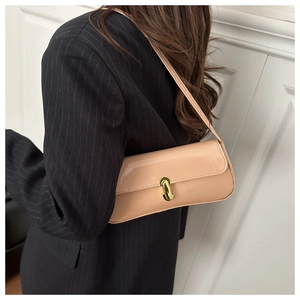 Close-up of beige patent leather baguette bag with a golden metal twist lock buckle