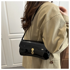 Glossy black patent leather underarm bag with gold buckle worn with a beige trench coat