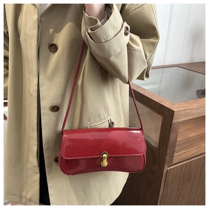 Detail of red patent leather baguette bag featuring a gold twist lock and smooth texture