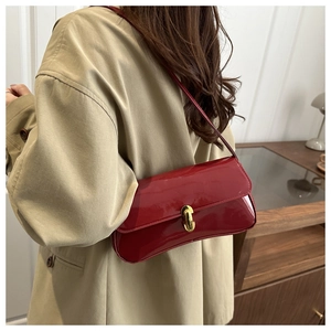 Close-up of vibrant red patent leather underarm bag with gold metal twist lock buckle