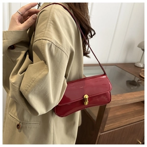 Chic red patent leather baguette bag with gold lock shown on model with trench coat
