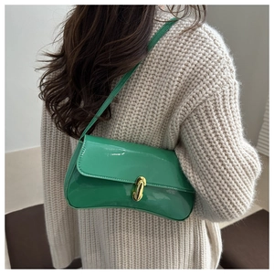 Detail of dark green patent leather baguette bag with a golden J-shaped twist lock buckle