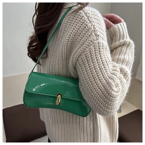 Close-up of green patent leather baguette bag with shiny gold metal buckle