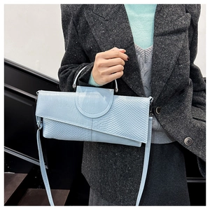 Detalle de bolso azul claro con textura de cocodrilo y correa de hombro extraíble