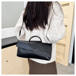 Modelo con bolso bandolera de cuero negro grabado con detalle de solapa de serpiente