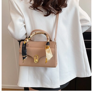 Detail of beige crossbody bag with patterned silk scarf handle and gold turn-lock