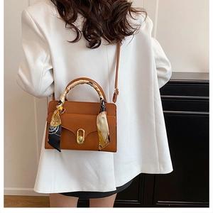 Brown leather handbag with decorative silk scarf handle and golden twist-lock closure