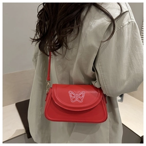 Gros plan du sac bandoulière rouge avec broderie papillon blanche et texture cuir lisse