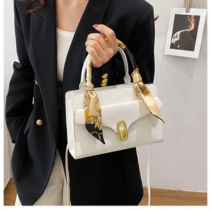 Detailed view of white leather crossbody bag with gold twist lock and floral silk scarf