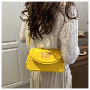 Détail du sac à bandoulière jaune avec broderie papillon rose et ferrures dorées