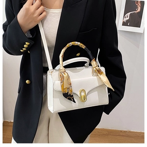 White faux leather handbag with gold buckle and silk scarf handle detail on model