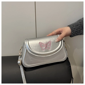 Vue détaillée du sac bandoulière argenté avec broderie papillon rose délicate