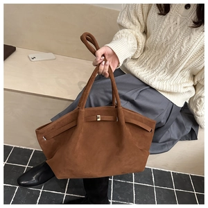 Dettaglio di una borsa a tracolla in pelle scamosciata marrone con fibbia in metallo