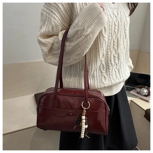 Detail of dark red vintage tote bag with glossy leather and decorative bead tassel pendant