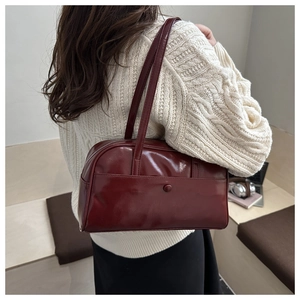 Detail view of burgundy leather tote bag styled with a white knit sweater on model
