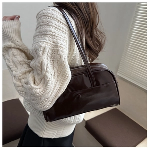 Close-up of a glossy chocolate brown hobo bag with reflective patent leather texture