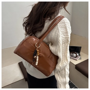 Detail of caramel brown leather shoulder bag with bead tassel and decorative pocket