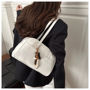 Detail of white faux leather shoulder bag with decorative wooden beads and metal zipper