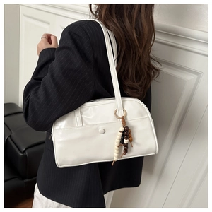 Detail of cream white faux leather shoulder bag with decorative wooden beads and front pocket
