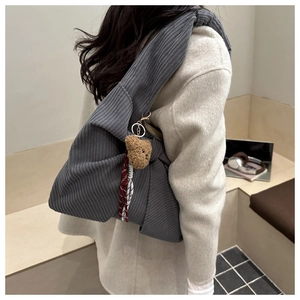 Detail view of dark grey corduroy tote bag with plush bear charm on a wide shoulder strap