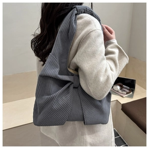 Détail d'un sac bandoulière en velours côtelé gris avec nœud sur une femme