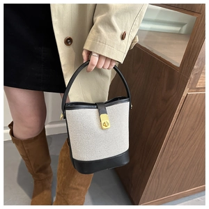 Detail of canvas bucket bag with black leather trim and golden twist lock closure