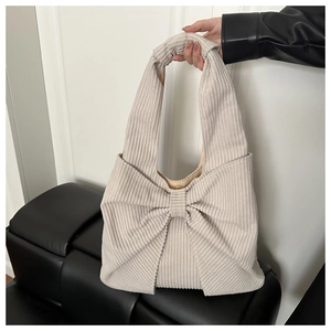 Détail du sac à bandoulière en velours côtelé beige avec grand nœud et fermoir magnétique