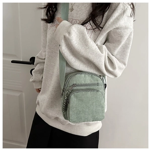 Détail du petit sac bandoulière en velours côtelé vert clair avec plusieurs fermetures