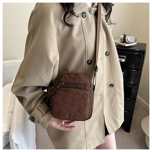 Gros plan détaillé de la texture du sac en velours côtelé marron et compartiment zippé