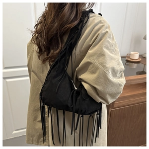 Détail du sac bandoulière en tissu noir avec longues franges et forme de croissant