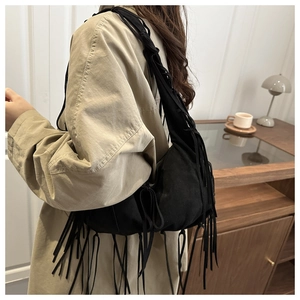 Détail du sac à bandoulière noir à franges avec pompons bohèmes et texture suédée
