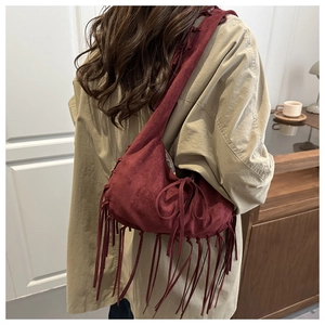 Gros plan d'un sac en daim bordeaux avec de longues franges et des détails bohèmes