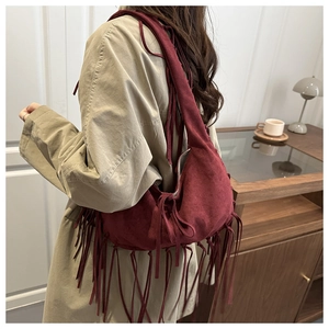 Détail latéral d'un grand sac cabas en daim bordeaux avec de longues franges