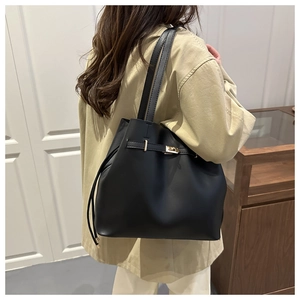 Detail of classic black leather tote bag featuring a golden twist lock and drawstring side