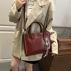 Sac fourre-tout rouge foncé brillant en cuir avec logo doré et pendentif chocolat