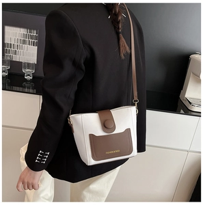 Bolso cubo moderno en blanco y marrón con correa ajustable mostrado sobre una modelo