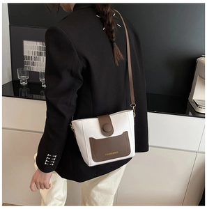 Vista detallada del bolso cubo bicolor con bolsillo marrón llevado por modelo