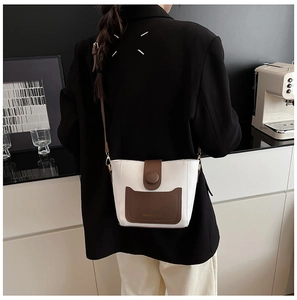 Detalle de un bolso tipo cubo bicolor en cuero blanco y marrón sobre una modelo real
