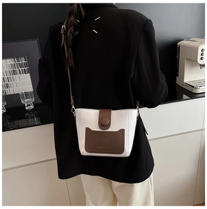 Bolso saco blanco minimalista con detalle de bolsillo marrón y correa en una modelo