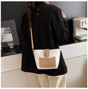 Vista trasera de una modelo con el bolso de hombro bicolor blanco y marrón en sala