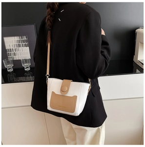 Detalle de bolso cubo bicolor en blanco y caqui con correa fina de cuero para mujer
