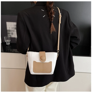 Detalle de un bolso cubo bicolor con bolsillo caqui y correa ajustable de hombro