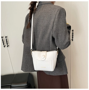 Detalle del bolso tipo cubo blanco en cuero PU con hebilla redonda y herrajes dorados