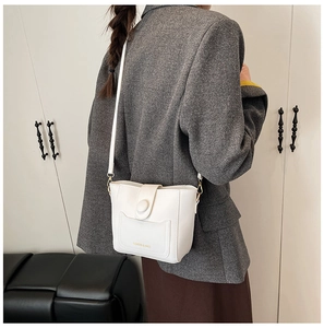 Detalle del bolso tipo cubo blanco con herrajes dorados y letras doradas de calidad